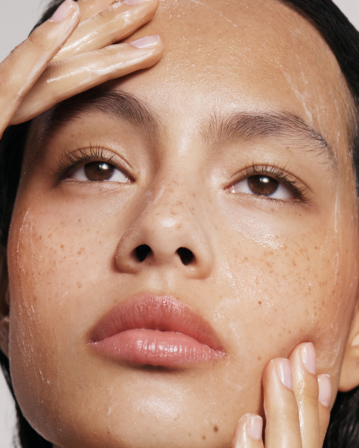 Model applying skincare on clean skin.